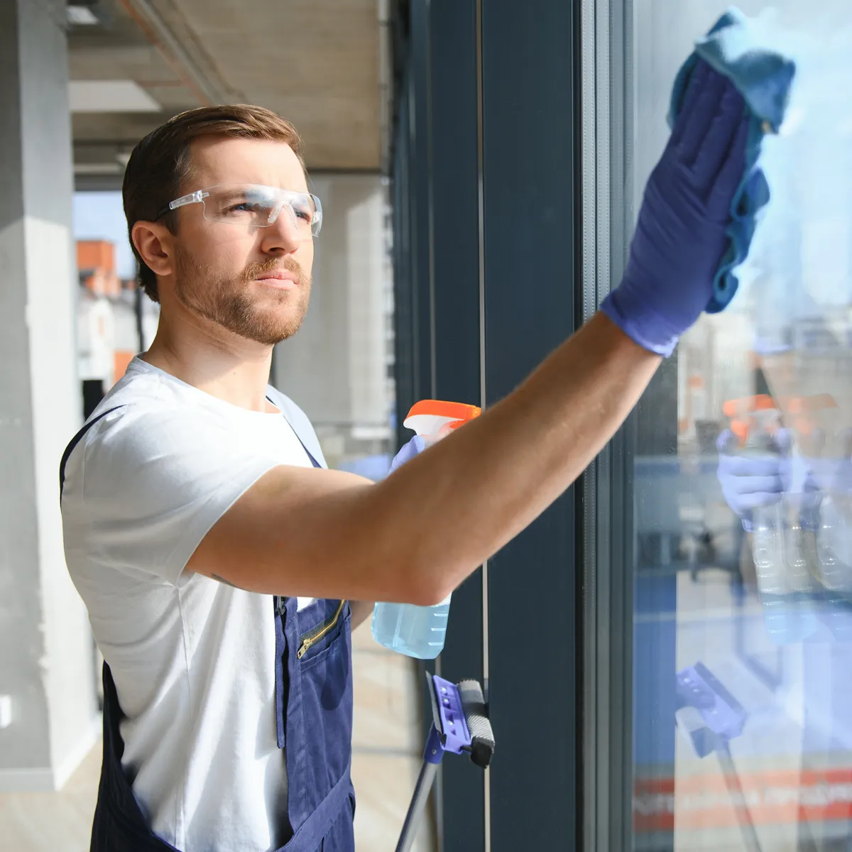 Operatore con occhiali di protezione durante pulizia professionale vetri e finestre a Bari con spray specifici e panno microfibra. Impresa di pulizie Bari specializzata in lavaggio vetrate per uffici, negozi e edifici commerciali con tecnici esperti e dispositivi di sicurezza certificati. Servizio di pulizia vetri accurato che garantisce trasparenza perfetta e risultati impeccabili per ogni superficie vetrata con massima attenzione alla sicurezza.